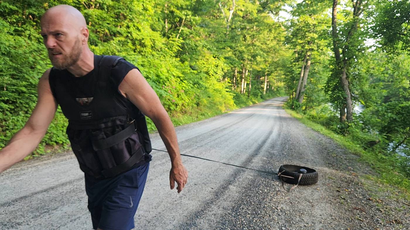 Rob dragging a homemade tire sled down a gravel road